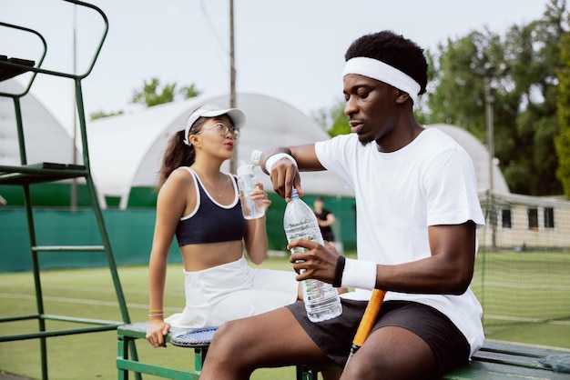 Two best friends sat down to rest on bench after playing tennis