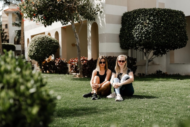 Two best girlfriends in sportswear and sunglasses hug tightly