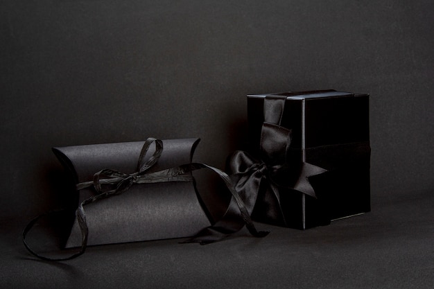 Two black gift boxes with ribbon bow on dark background