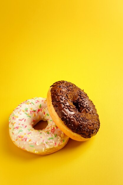 Two black and white donuts on yellow wall