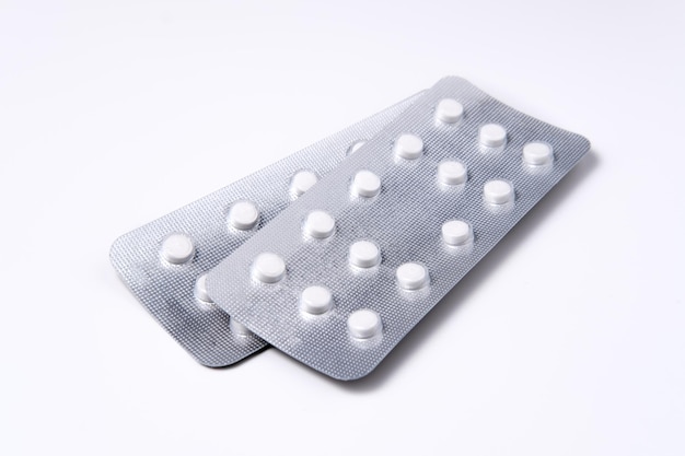 Two blisters with white medical pills isolated on graywhite background