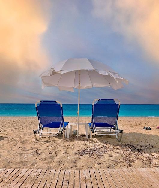 Two blue beach chairs with an umbrella on the beach