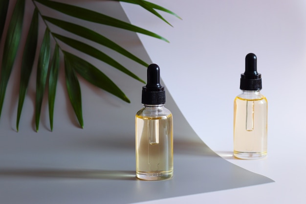 Two bottles of cosmetic essential oil and palm leaf Serum skin care and antiaging cosmetic product