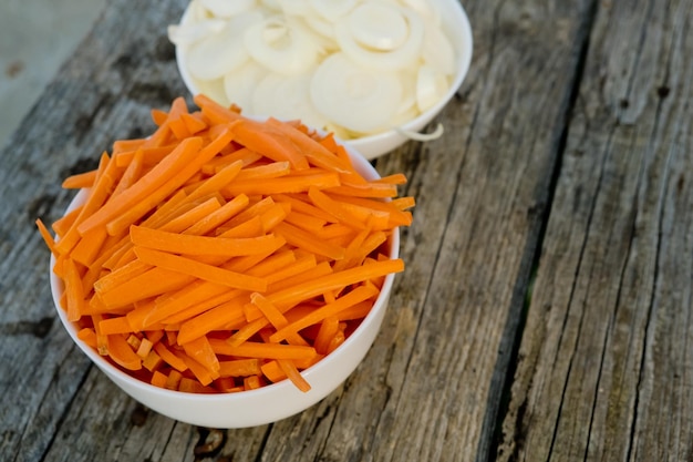 Two bowl full of orange carrot sticks and sliced white onion Close up Selective focus