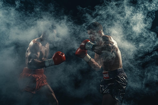 Photo two boxers in red boxing gloves in the dark