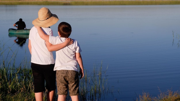 Two boys are looking at man in a board in the lake