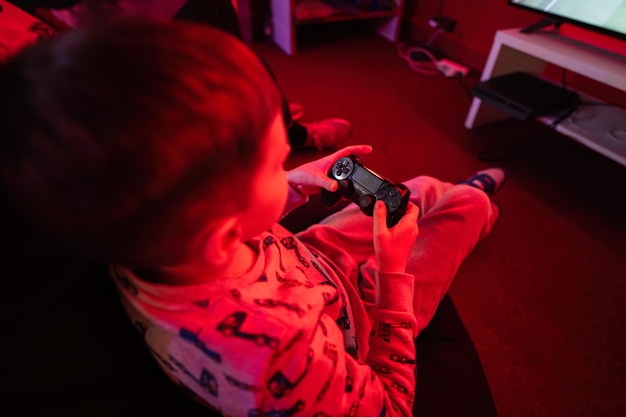 Two boys gamers play gamepad video game console in red gaming room