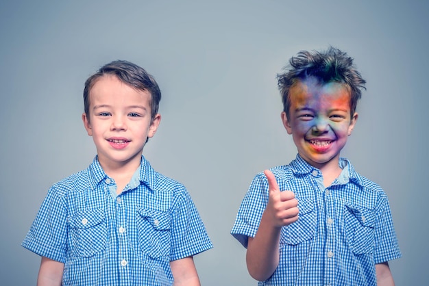 Two boys with a clean and painted face on a gray background Toned