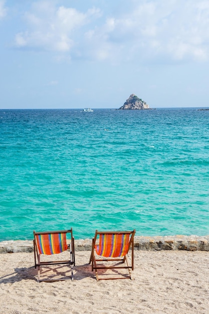 Two bright colored sun loungers against the backdrop of the turquoise sea and rocks