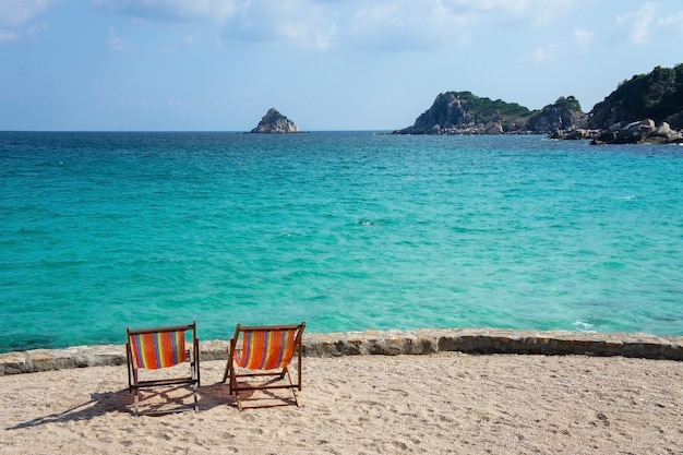 Two bright colored sun loungers against the backdrop of the turquoise sea and rocks