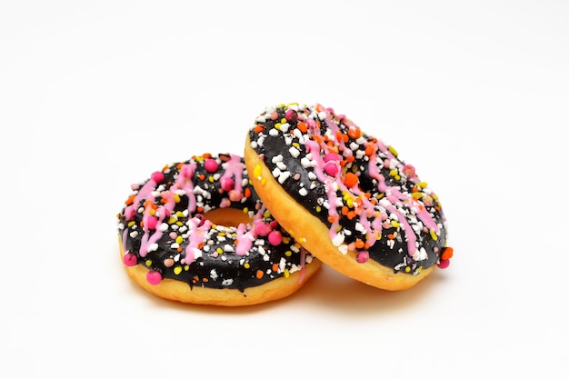 Two bright donuts in chocolate icing and pink sprinkles closeup on a white background