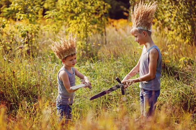 Two Brothers have a crown from dry grass on the head and swords in hands.