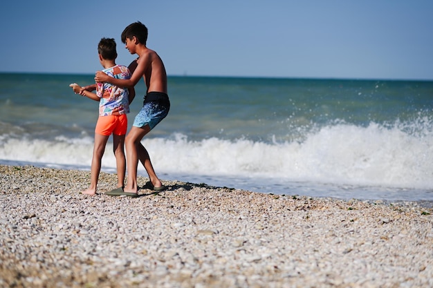 Two brothers throw pebbles into the sea in beach Porto Sant Elpidio Italy