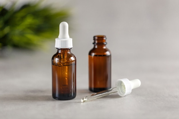 Two brown dropper bottles on a gray background