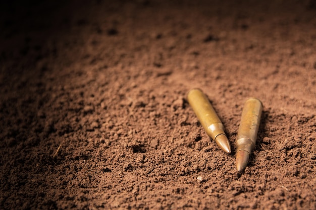 Two bullets, machine gun bullets on soil background