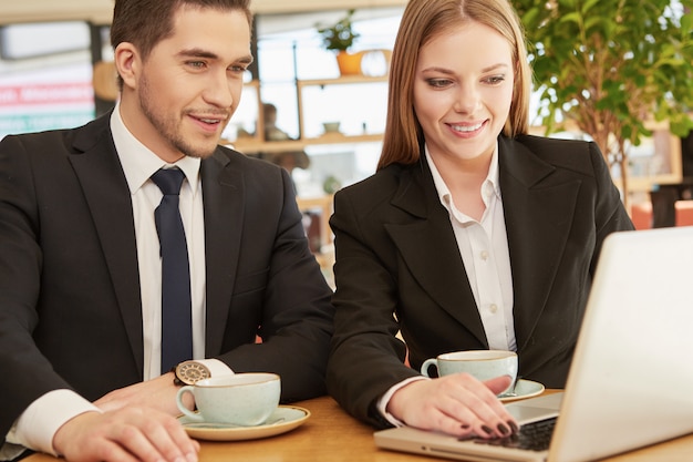 Two business colleagues using laptop at the cafe