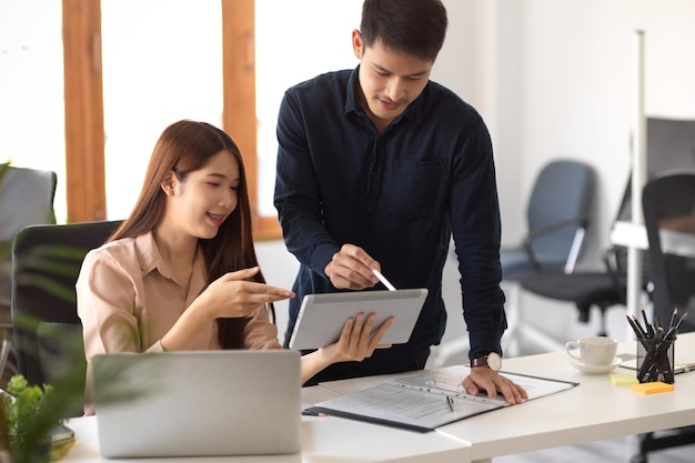 Two business coworker looking the details at tablet screen and discussing their business plan