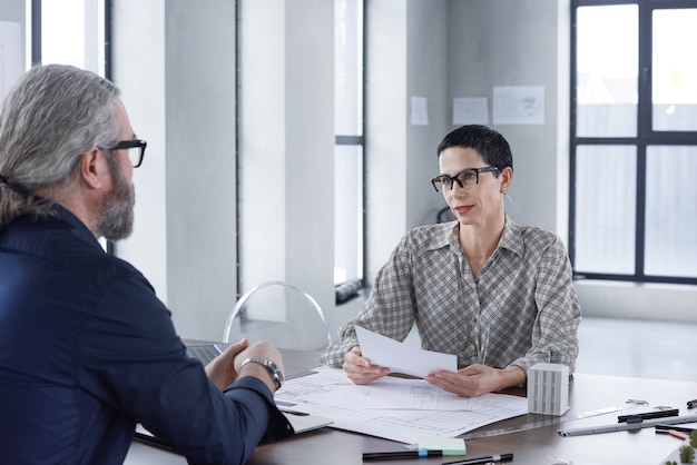 Two business partners sitting at the table and discussing business project together during meeting at office