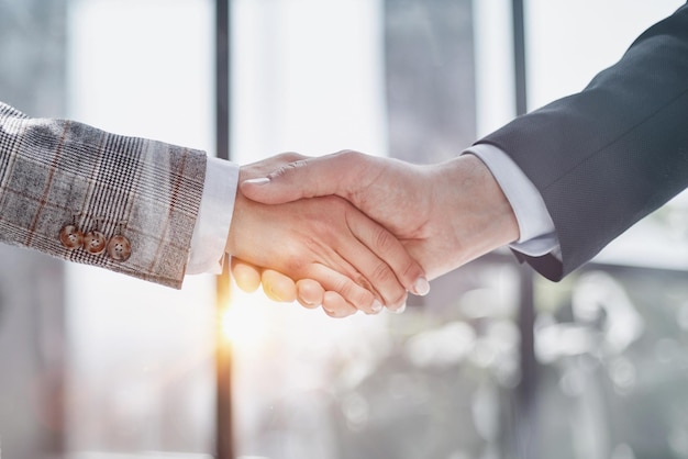 Two business people shaking hands in front of their colleagues