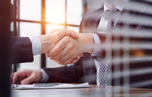 Two business people shaking hands in front of their colleagues