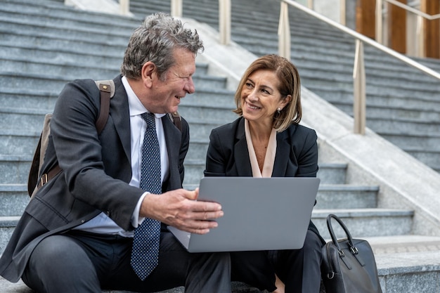 Two business people talking about project strategy outside businessman discuss project planning with female colleague while having conversation and advice on financial data report