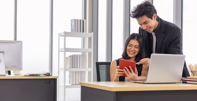 Two business people working together with smile on face using tablet at the office