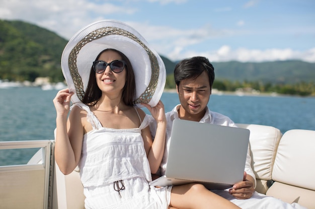 Two business people working with laptop on a sailing boat sailing trip