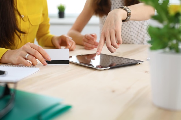 Two business woman or friends are talking and using tablet computer.