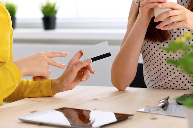 Two business woman or friends are talking and using tablet computer.