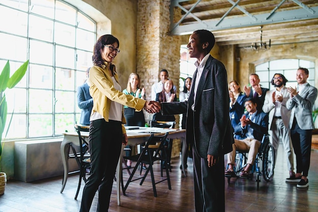 Two business women one of Japanese ethnicity the other African shake hands