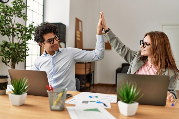 Two business workers smiling happy high five at the office.