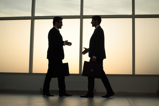 Two businessmen are walking towards each other