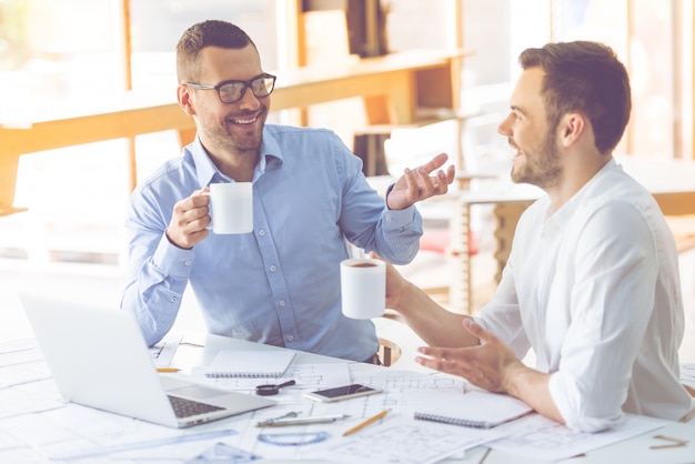 Two businessmen in classic shirts are drinking coffee.