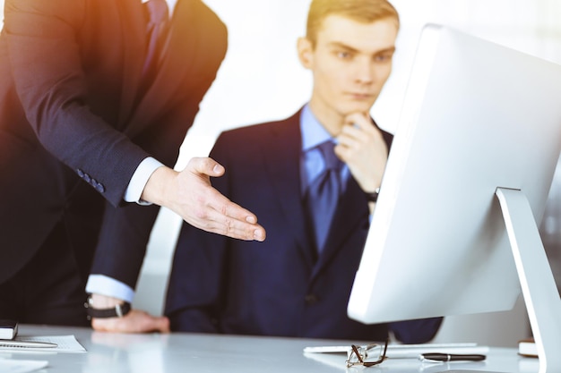 Photo two businessmen discussing questions at a meeting in a sunny modern office using a computer