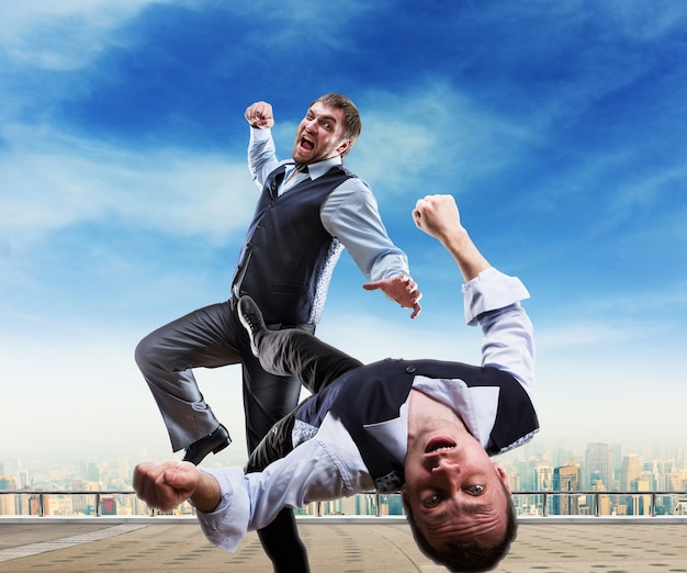 Two businessmen fighting on the roof