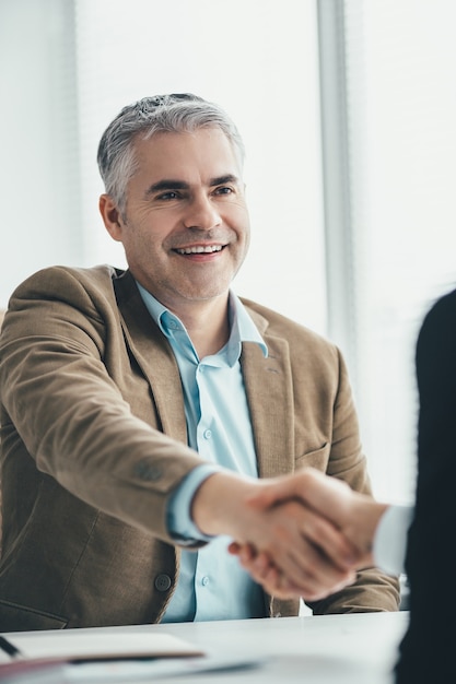 The two businessmen handshaking in the office