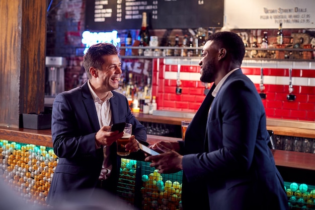 Two Businessmen Meeting For Drinks And Socializing In Bar After Work