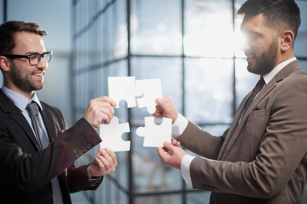 Two businessmen put together a puzzle opposite each other