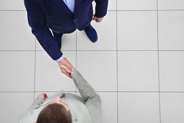 Two businessmen shaking hands on grey background