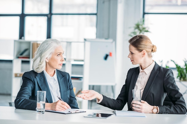 Two businesswomen gesturing and discussing business project on meeting in office