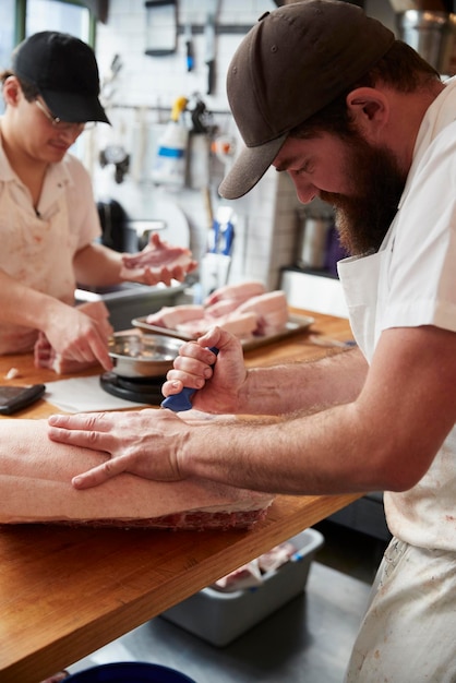 Two butchers preparing meatcuts of meat in a butcher39s shop vertical