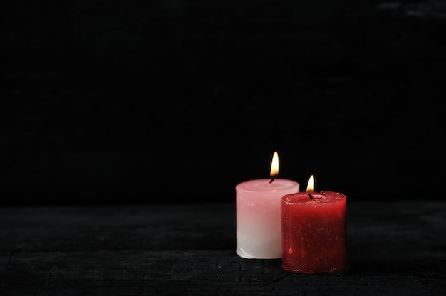 Two candles with lit fire on black background