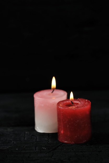 Two candles with lit fire on black background