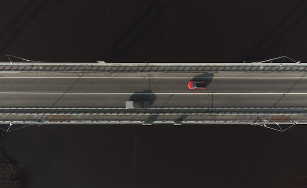 Two cars driving in different directions on the road bridge over the river Top view