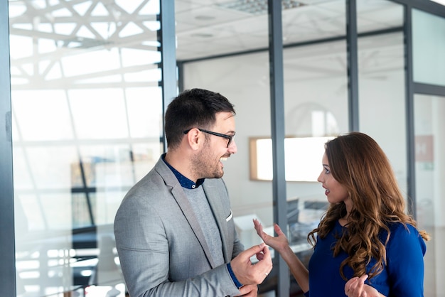 Two Caucasian business people consulting in front of the company's office.