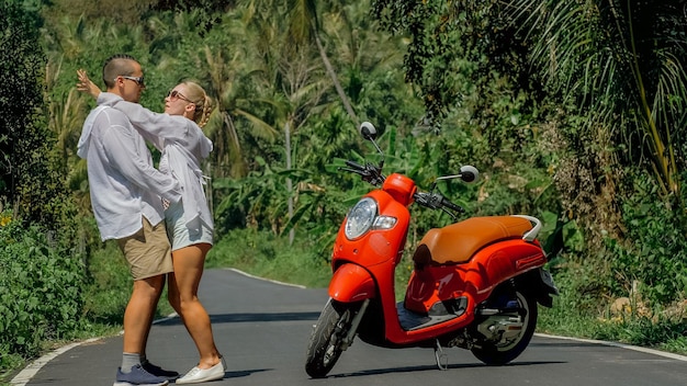 Two caucasian tourist woman man dance near scooter Love couple on red motorbike