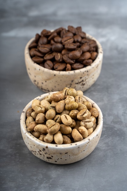 Two ceramic cups,  different stages of coffee, green bean, roasted bean, coffee