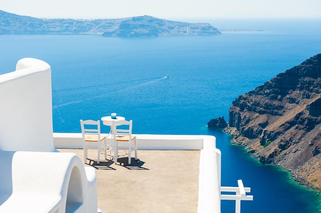 Two chairs on the terrace with sea view. White architecture on Santorini island, Greece. Travel destinations concept