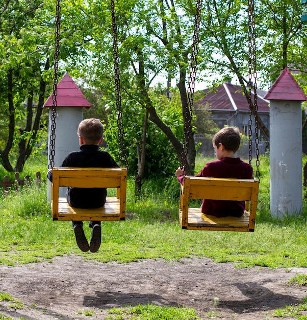 Two cheerful boys ride on swing