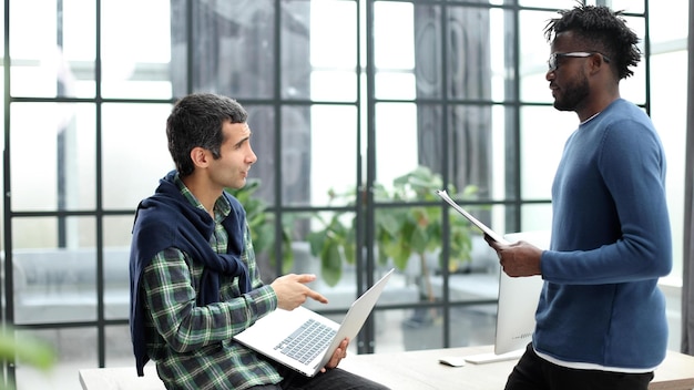 Two cheerful businessmen discussing something on the laptop in an office